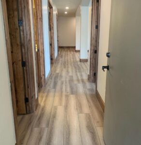A renovated hallway with new flooring and wooden doors installed by Halpin Hands in Williams, OR.