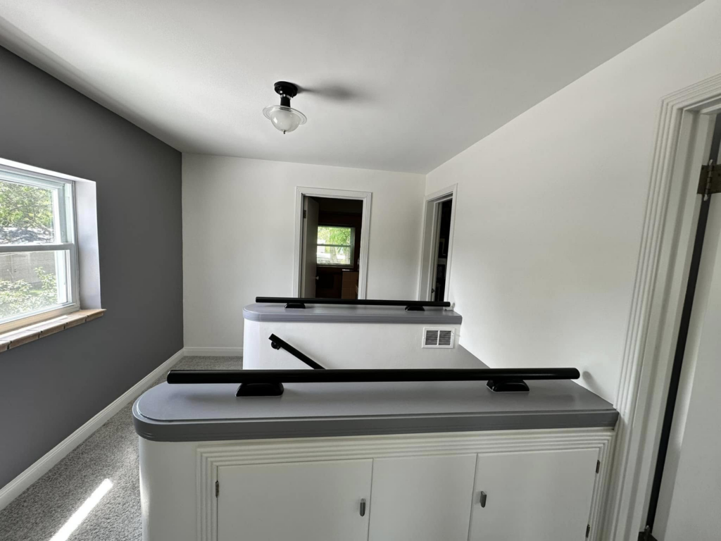 A newly painted hallway with gray and white walls, featuring railings, completed by EJ Drywall Plus in Kearney, NE.