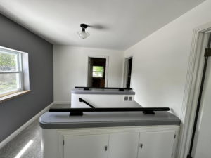 A newly painted hallway with gray and white walls, featuring railings, completed by EJ Drywall Plus in Kearney, NE.
