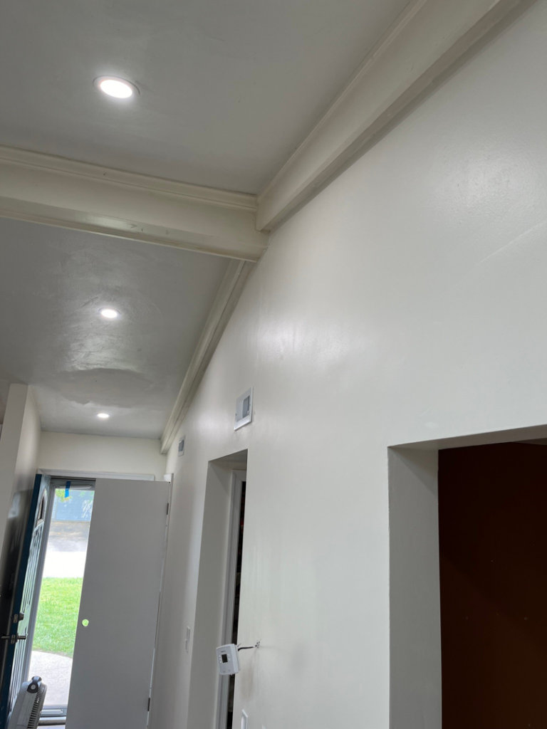 A freshly painted hallway with new recessed lighting and crown molding installed by Precision Home Improvement in Massapequa, NY.