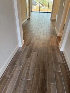 A hallway showcasing newly installed wood-look tile flooring, a project by Roaring Lion Renovations, LLC in Houston, TX.