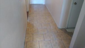 Hallway tile installation in progress with spacers visible, demonstrating a handyman flooring service by MG'S Services LLC in Albuquerque, NM.