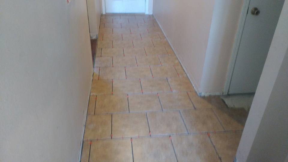 Hallway tile installation in progress with spacers visible, demonstrating a handyman flooring service by MG'S Services LLC in Albuquerque, NM.