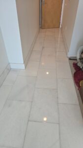 A hallway with gleaming white polished tile floors, showcasing work by Cornerstone Services Management in Miami, FL.