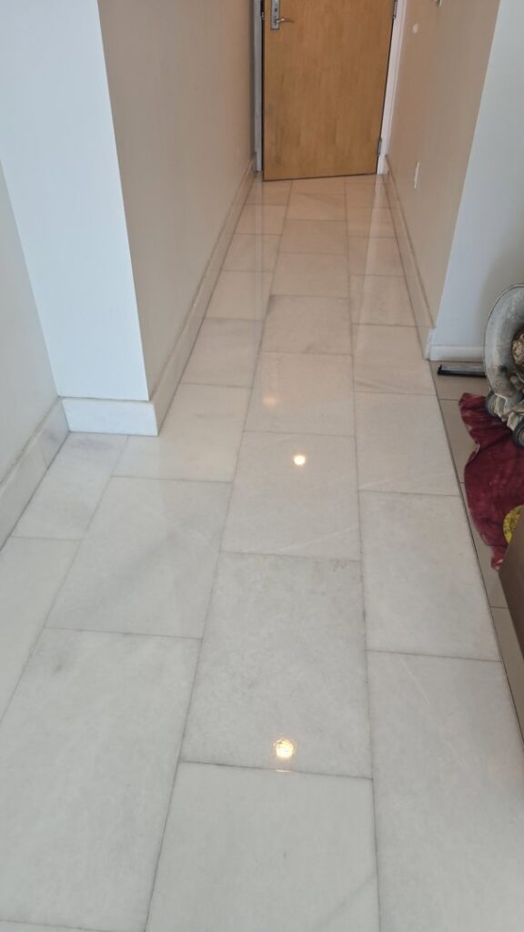A hallway with gleaming white polished tile floors, showcasing work by Cornerstone Services Management in Miami, FL.