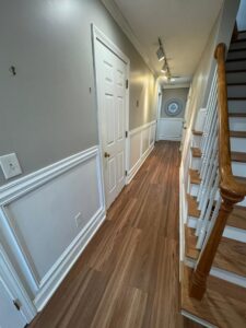 A renovated hallway featuring new wainscoting, crown molding, and hardwood flooring installed by Quinonez Painting & Renovations LLC in Providence, RI.