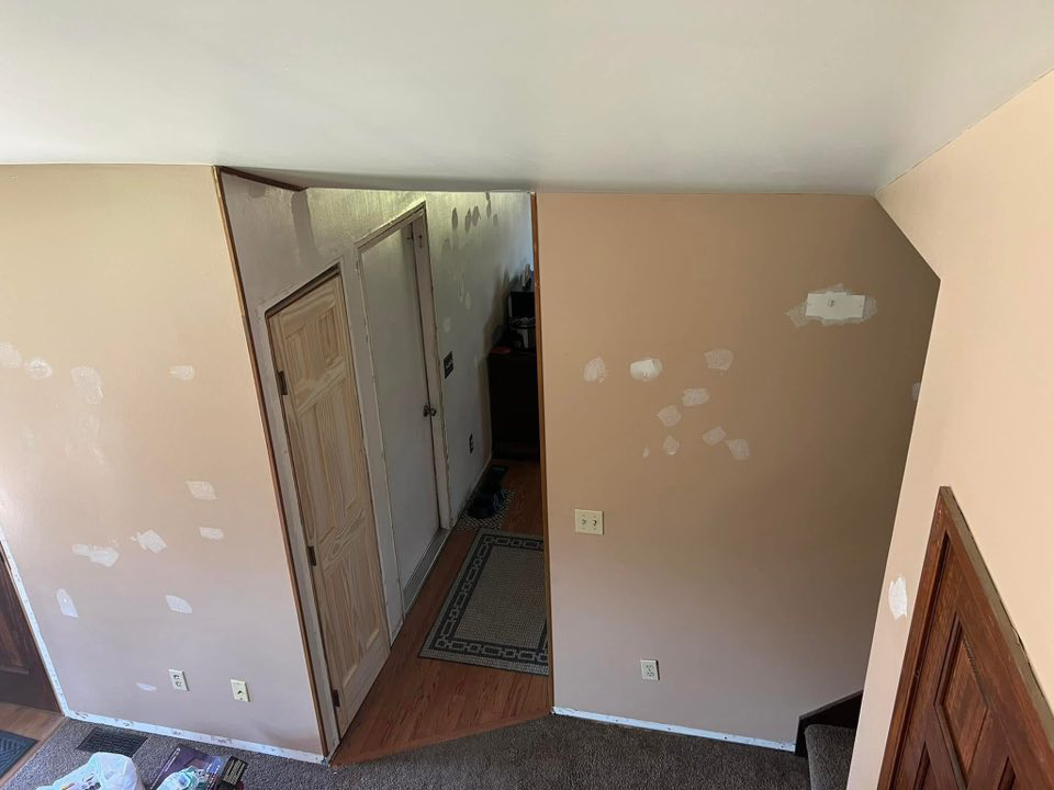 A hallway with walls prepped for repair and painting, showing handyman work in progress by Honest Help in Fort Wayne, IN