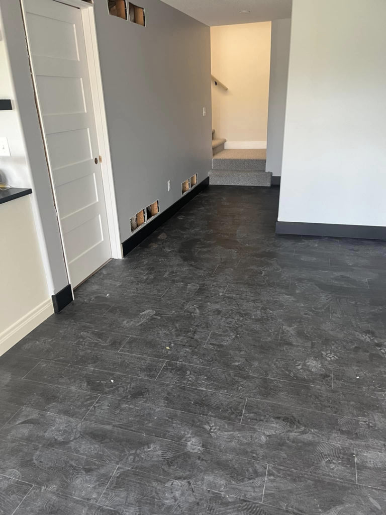 A hallway featuring new dark flooring, black baseboards, and wall cutouts for electrical work, completed by Drew's Home Repair and Handyman Service in Wichita, KS.