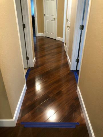 A hallway featuring newly installed dark wood flooring with painter's tape, completed by Stormtroopers Home Improvement in Port St. Lucie, FL.