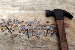 A hammer and nails on a wooden surface, representing handyman services by Peak2Peak Connect Handyman Services LLC in Arvada, CO.