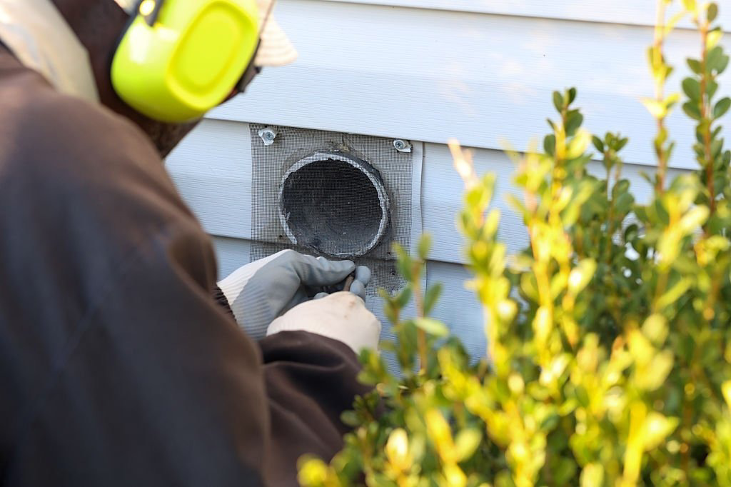 A hand uses a specialized brush to clean the lint trap area of a dryer for SafeVent Dryer Vent Cleaning in Wilmington, NC.