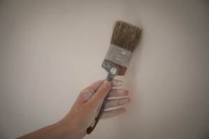 A hand holding a paint brush, ready for a painting job by Fastrac Painting in Ann Arbor, MI