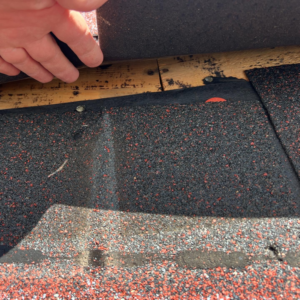 A close-up of a hand installing or repairing roof shingles, a service by GOAT Services, LLC in Louisville, KY.