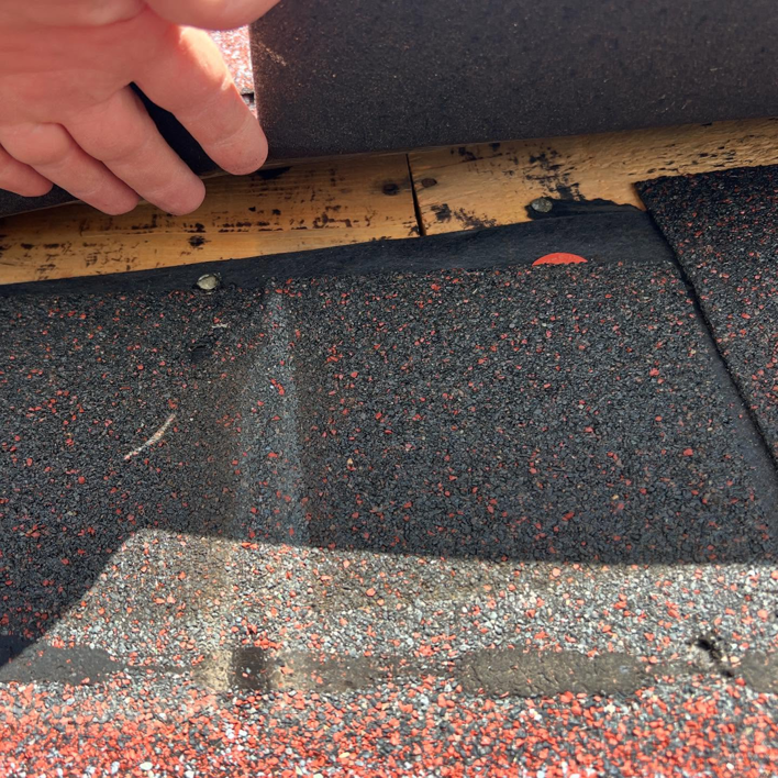 A close-up of a hand installing or repairing roof shingles, a service by GOAT Services, LLC in Louisville, KY.