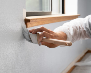 A handyman's hand painting a wall with a brush for A 'n' G Residential in Amsterdam, NY.