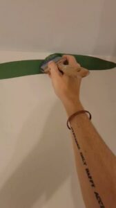 A hand carefully painting a green stripe on a wall, demonstrating precision work by Prime Painting in Charlotte, NC.
