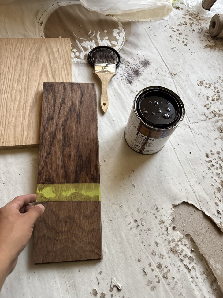 Hand staining wood with a brush and can of stain, showing painting services by New Era Painting & Construction, Jefferson, NC.