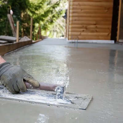 A gloved hand using a trowel to smooth a wet concrete surface, showcasing work by concrete poured & installed - cp&i in Buffalo, NY.