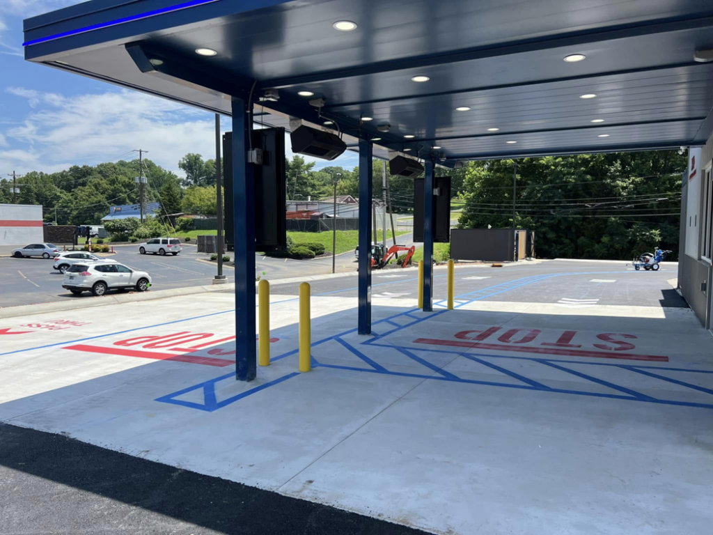 Handicap parking and STOP markings under a drive-thru canopy by Marine One Striping in Clarksville, TN.