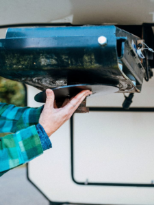 Hands working on the installation or maintenance of a fifth-wheel trailer hitch by Handyman Vehicle Outfitters in Portland, ME.