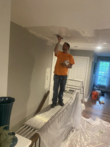 A handyman applying drywall compound to a ceiling while standing on a scaffold for Walrus Rock Construction LLC in Pacific, MO.
