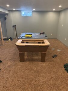 A handyman from Jewell Services assembling a pool table, providing furniture assembly services in Des Moines, IA.