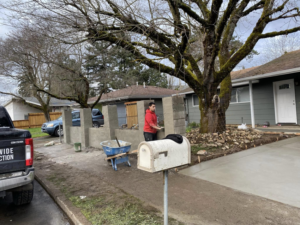 A handyman constructing a concrete block wall along a driveway for WorldWide Construction LLC in Portland, OR.