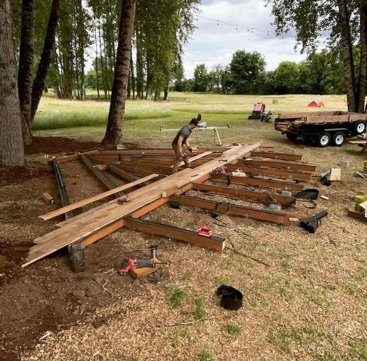 A handyman constructing a new deck frame outdoors, showcasing deck building services by Kalau Builders LLC in Eugene, OR.