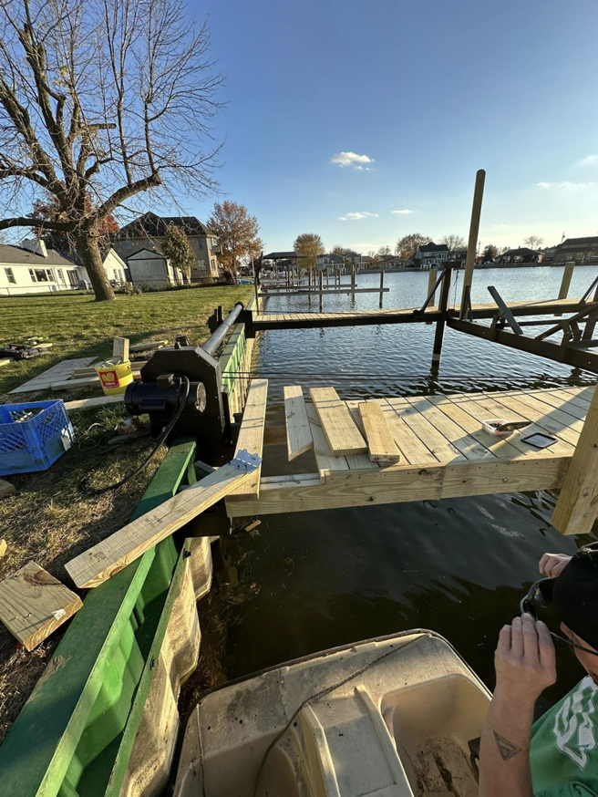 A handyman working on the construction of a new wooden dock by TopNotch Remodeling & Restoration Service LLC in Warren, MI