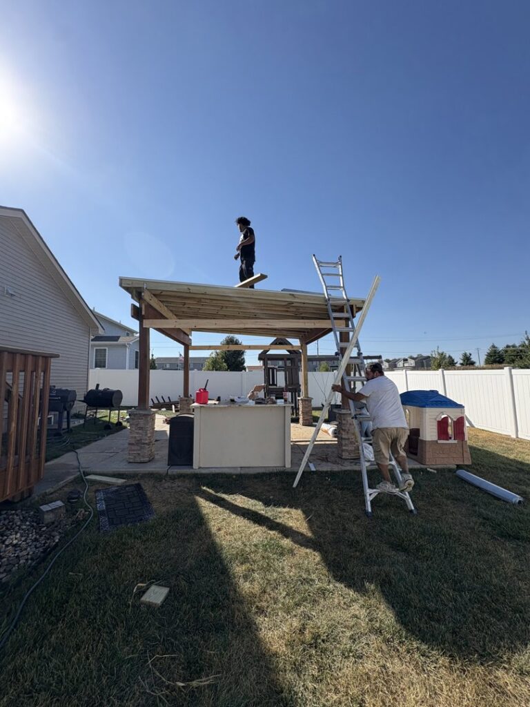 Handymen from Jewell Services constructing an outdoor pergola or patio roof structure in Des Moines, IA.