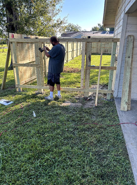 A handyman actively building a wooden fence structure with a power tool for Verkler Development LLC in Lake Charles, LA.