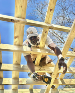 A handyman from Unto GOD's Kingdom Builders working on building a wooden structure or deck frame in Mint Hill, NC.