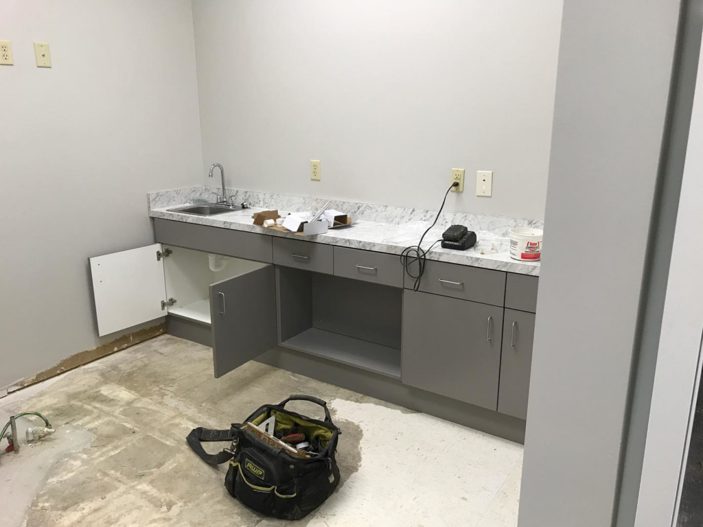 Handyman installing new cabinets and a sink in a commercial space for Savage Construction in Cordova, TN.