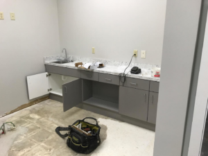 Handyman installing new cabinets and a sink in a commercial space for Savage Construction in Cordova, TN.