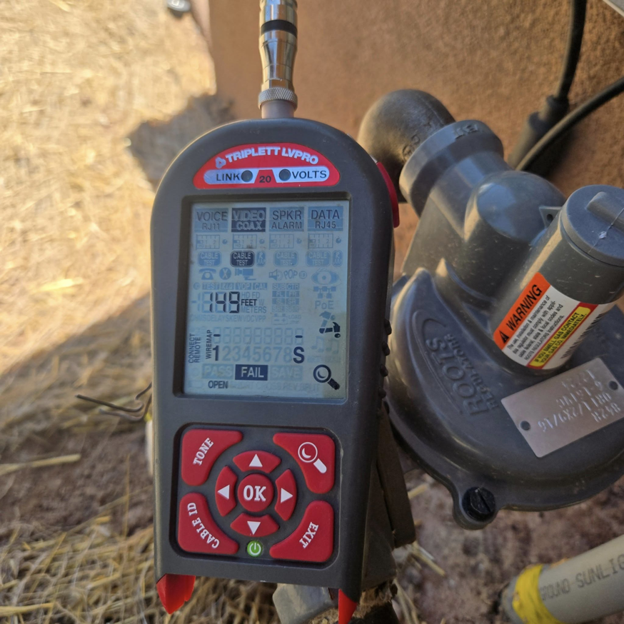 A handyman from Mock-n-Son Inc. in Rio Rancho, NM, uses a cable testing diagnostic tool showing a "FAIL" result.