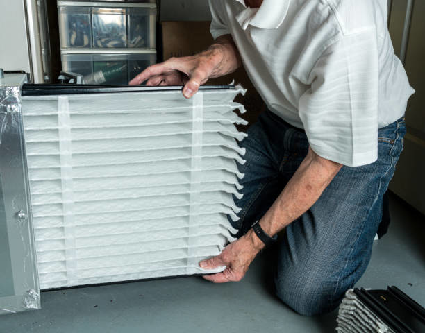 A handyman changing an HVAC air filter, a service provided by Quality Services, LLC in Alexandria, VA.