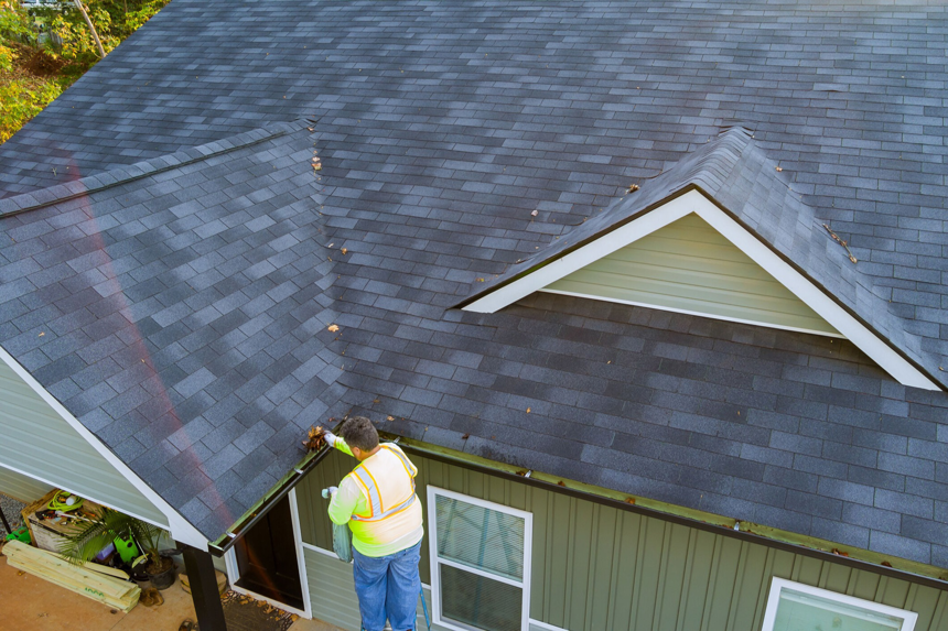 A handyman from Advanced Roofing Solutions, LLC cleaning gutters on a residential home in Blountville, TN.