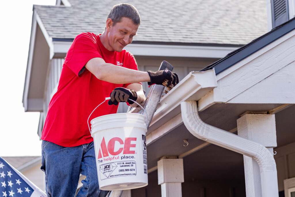 A handyman from Ace Handyman ABQ SF cleaning gutters while on a ladder in Albuquerque, NM