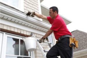 A Mr. Handyman professional cleaning gutters from a ladder on a residential home in Northern Pittsburgh, PA.