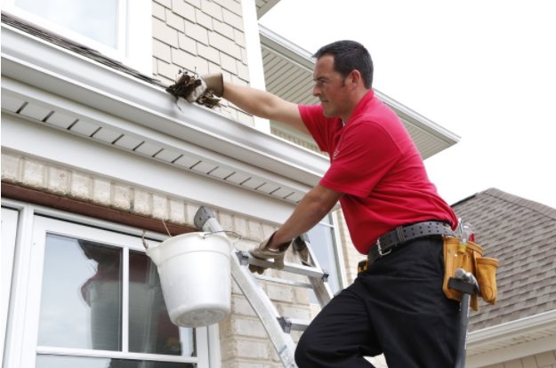 A Mr. Handyman professional cleaning gutters from a ladder on a residential home in Northern Pittsburgh, PA.