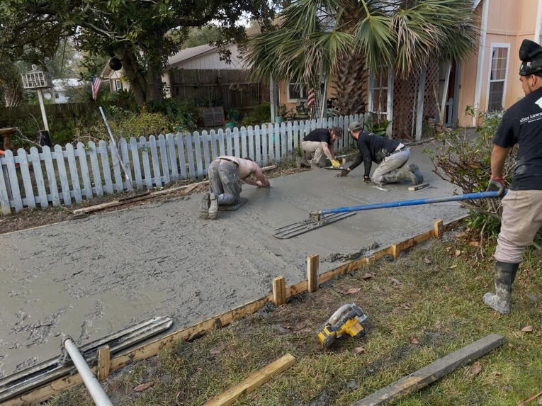 A handyman crew pouring and leveling a new concrete driveway for a client in Gulf Shores, AL, by Unified Roofing and Exteriors.