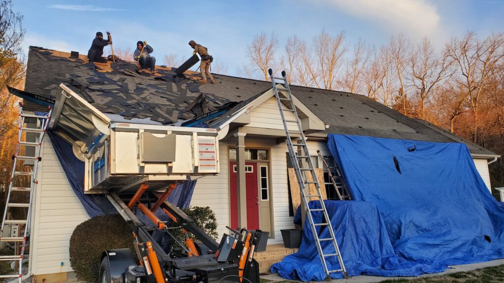 A handyman crew removing old shingles from a residential roof for Bayside Exteriors in Lewes, DE.