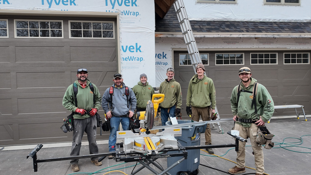 A handyman crew with tools and new garage doors installed on a house by Urban Exteriors in Green Bay, WI.
