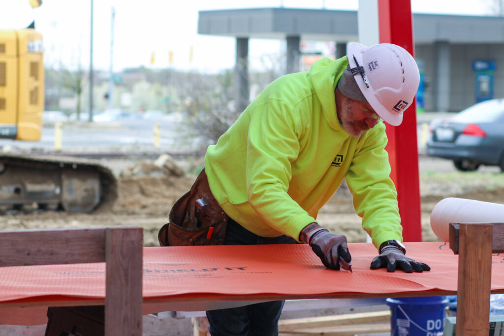 A handyman from EV Construction cutting building material with a utility knife in Holland, MI.