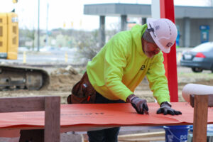 A handyman from EV Construction cutting building material with a utility knife in Holland, MI.