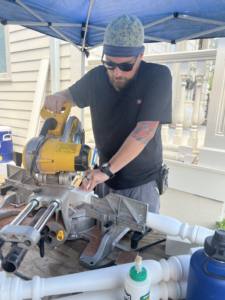 A handyman using a miter saw to cut wood for a porch railing installation by Ayres Endeavors, LLC in New Orleans, LA.