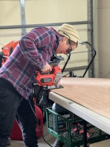 A handyman cutting a piece of wood with a jigsaw for a project by Med City Handy Ma'am in Rochester, MN