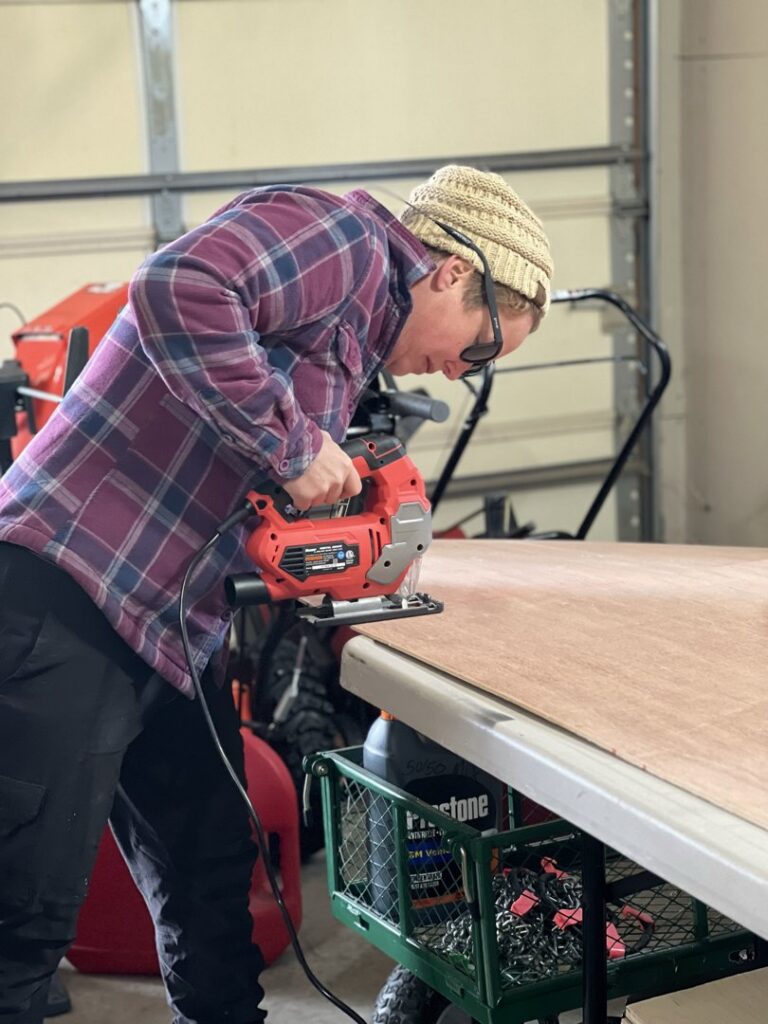 A handyman cutting a piece of wood with a jigsaw for a project by Med City Handy Ma'am in Rochester, MN