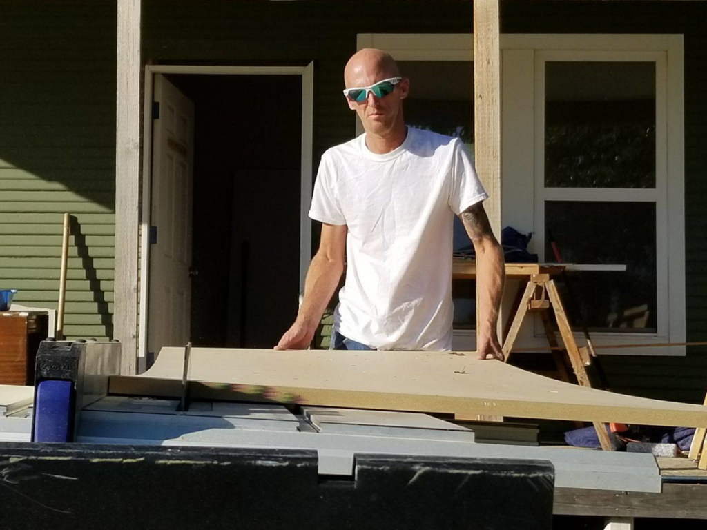 A handyman cutting a piece of wood on a table saw for KTL Home Repair and Remodeling in Norman, OK