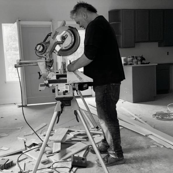 A handyman cutting wood trim with a miter saw for a project by Blackbird Custom Carpentry in Kansas City, MO.